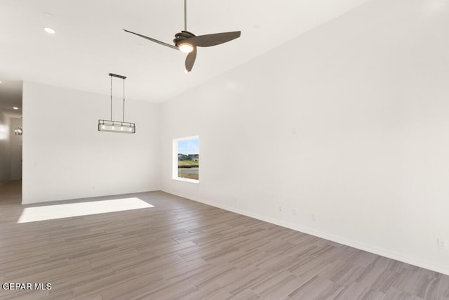 empty room featuring ceiling fan, baseboards, and wood finished floors