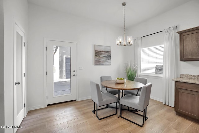 dining space featuring light wood finished floors, a chandelier, and baseboards