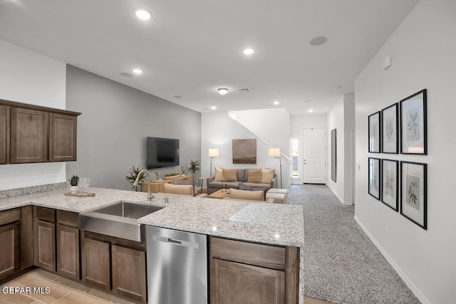 kitchen featuring dishwasher, a sink, a peninsula, light stone countertops, and baseboards