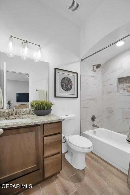 bathroom featuring vanity, wood finish floors, bathtub / shower combination, and toilet
