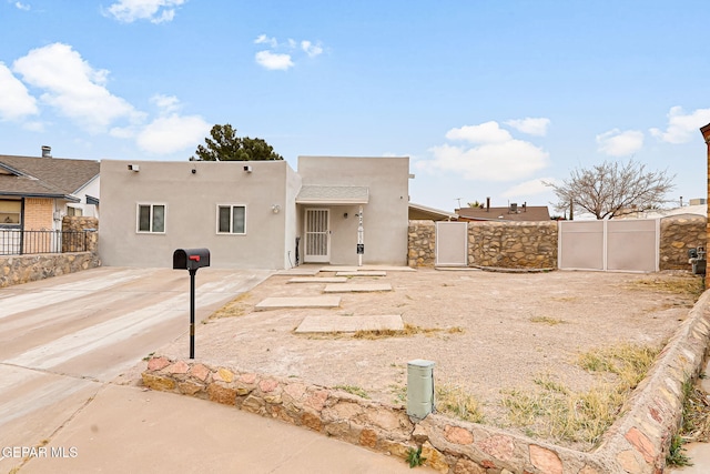 pueblo-style home with a patio area, fence, a gate, and stucco siding