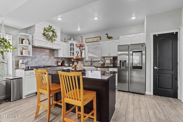 kitchen with white cabinetry, dark countertops, light wood-style flooring, and stainless steel appliances