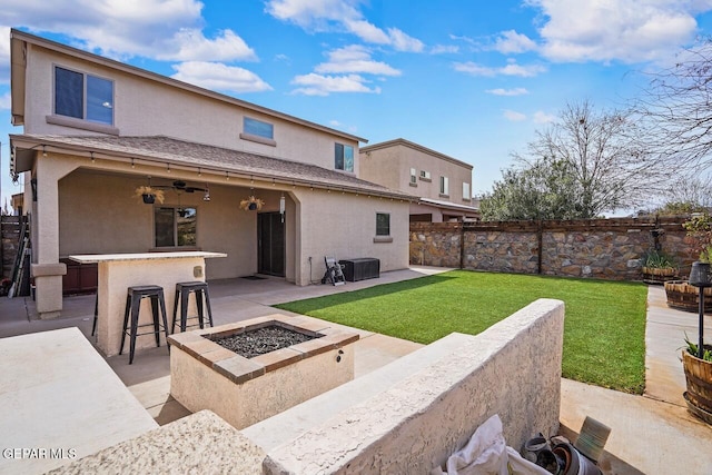 back of property featuring fence, an outdoor fire pit, stucco siding, a patio area, and outdoor dry bar