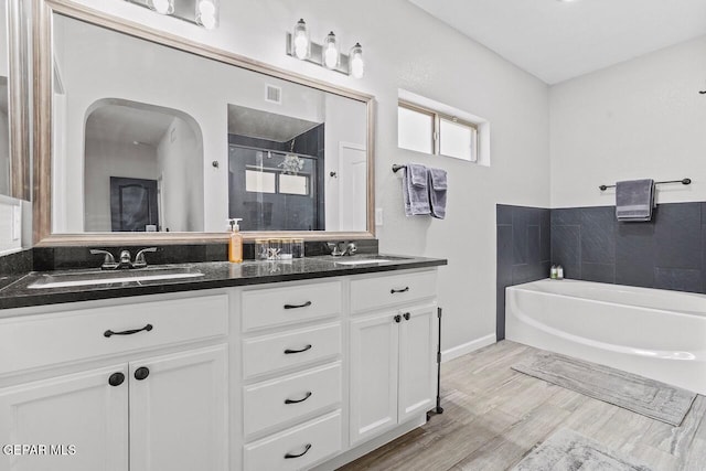 full bathroom with a shower stall, a garden tub, visible vents, and a sink