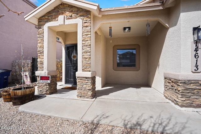 view of exterior entry featuring stucco siding and stone siding