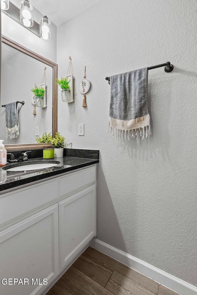 bathroom featuring vanity, wood finished floors, baseboards, and a textured wall