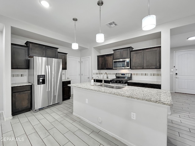 kitchen featuring visible vents, dark brown cabinetry, decorative backsplash, appliances with stainless steel finishes, and a sink