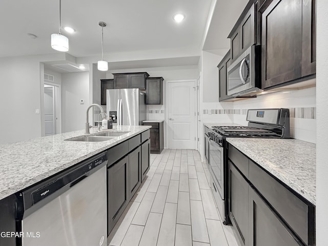 kitchen featuring wood tiled floor, a sink, stainless steel appliances, pendant lighting, and backsplash