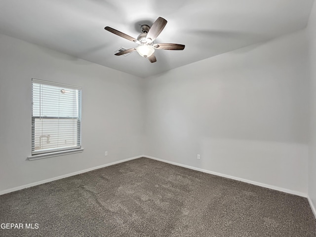 spare room featuring dark carpet, baseboards, and ceiling fan