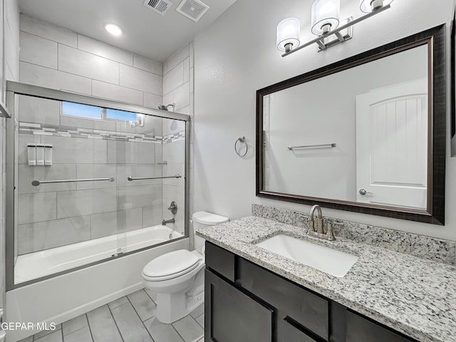 bathroom with visible vents, toilet, vanity, and bath / shower combo with glass door