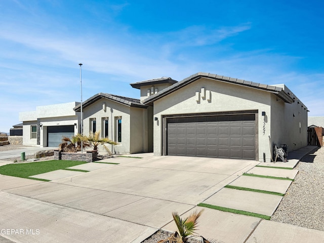 view of front facade with stucco siding, a garage, and driveway