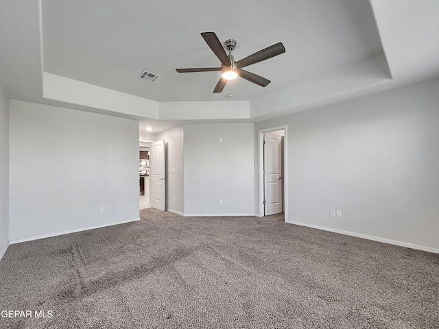 carpeted spare room with visible vents, baseboards, and a tray ceiling