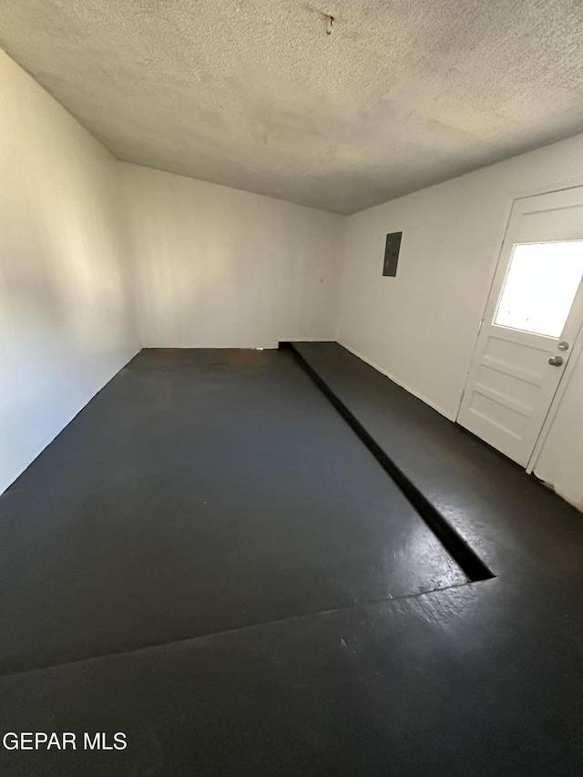 spare room with electric panel, a textured ceiling, and concrete flooring