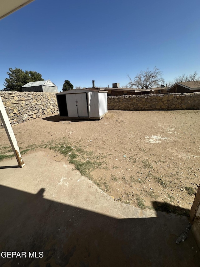 view of yard featuring a storage shed, an outdoor structure, and fence