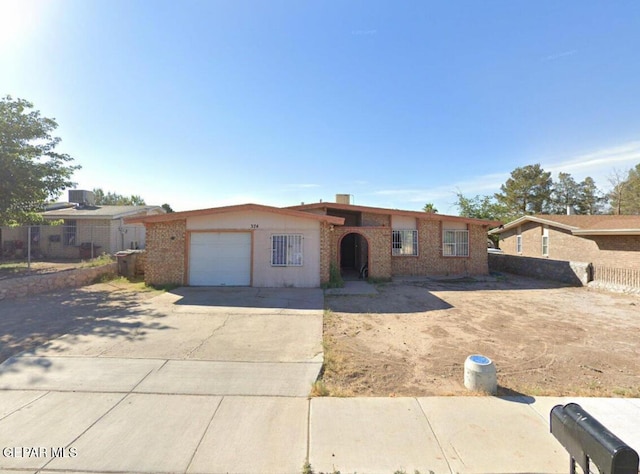 single story home featuring a garage, brick siding, driveway, and fence