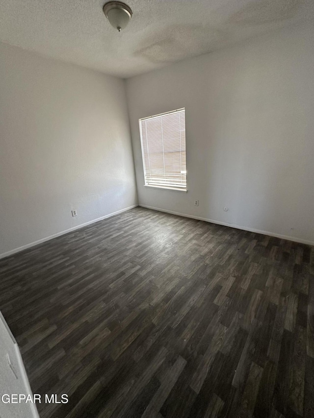 unfurnished room with baseboards, a textured ceiling, and dark wood-style floors