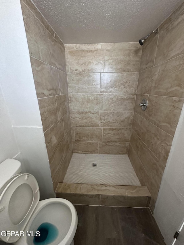 full bath with a shower stall, a textured ceiling, and toilet