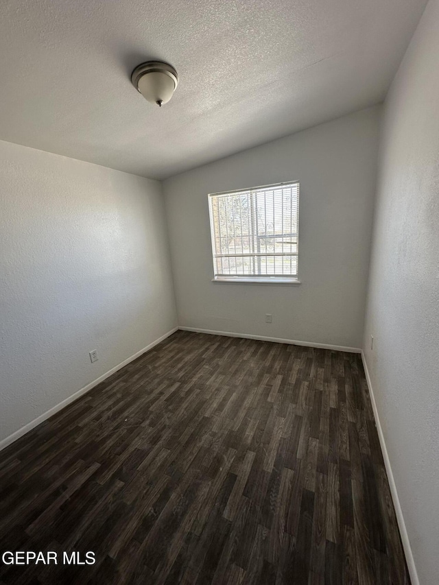 spare room featuring dark wood-type flooring, baseboards, and a textured ceiling