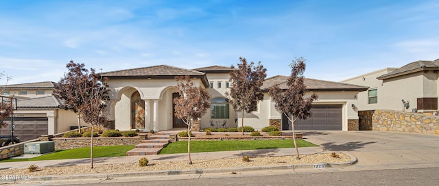 view of front of property with a tile roof, stucco siding, concrete driveway, an attached garage, and stone siding