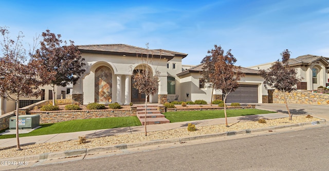 mediterranean / spanish-style home featuring a garage, concrete driveway, a front lawn, and stucco siding