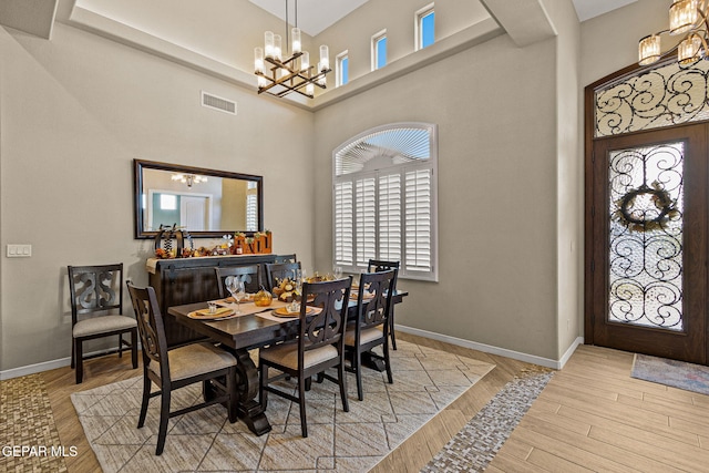 dining room featuring baseboards, visible vents, a chandelier, and wood finished floors