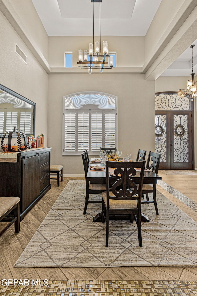 dining room featuring a chandelier, french doors, visible vents, and wood finished floors