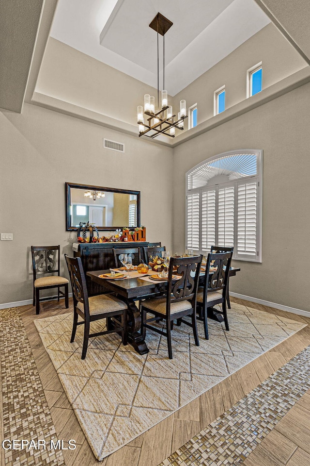 dining room with a chandelier, a tray ceiling, visible vents, and baseboards