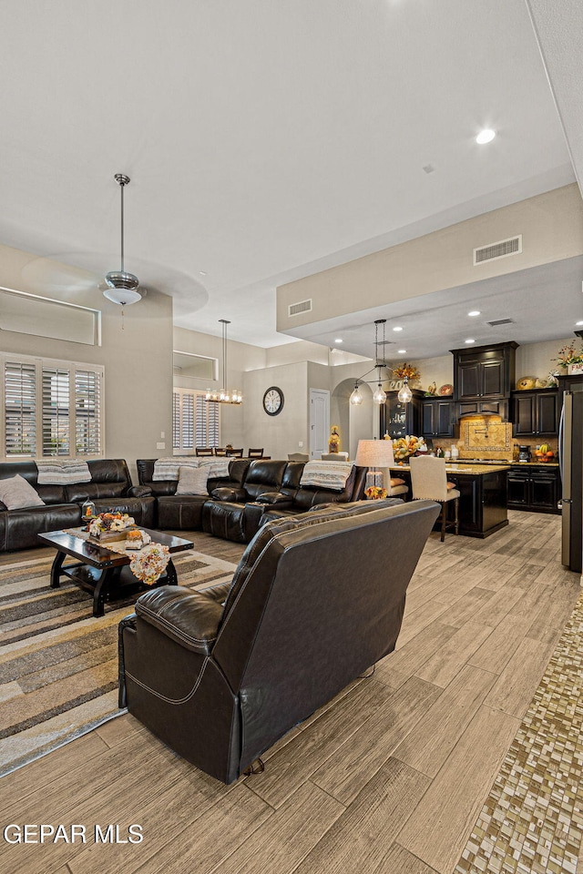 living area with light wood-type flooring, visible vents, a notable chandelier, and recessed lighting