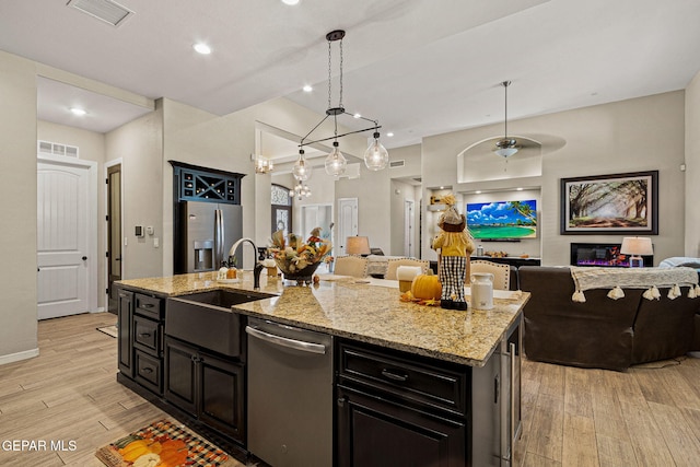 kitchen with visible vents, appliances with stainless steel finishes, open floor plan, dark cabinets, and light wood-type flooring