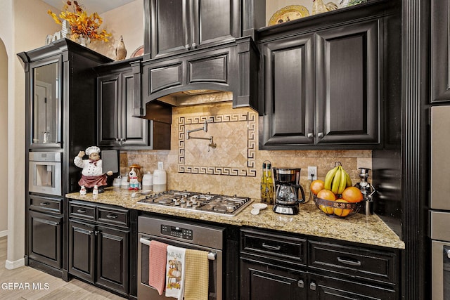 kitchen featuring appliances with stainless steel finishes, decorative backsplash, and dark cabinets