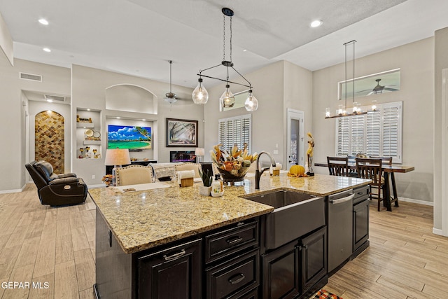 kitchen featuring visible vents, open floor plan, a sink, light wood-style floors, and stainless steel dishwasher