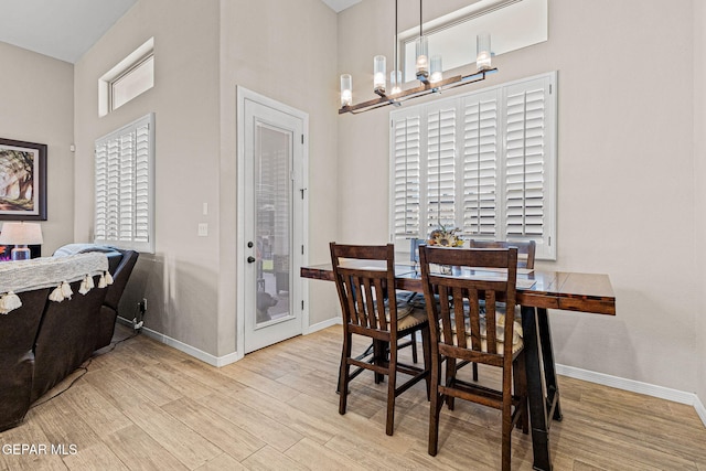 dining room featuring a chandelier, light wood-style flooring, and baseboards