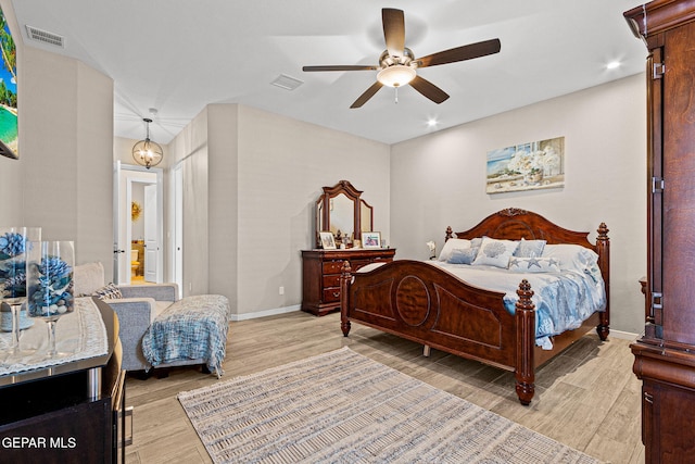 bedroom featuring a ceiling fan, visible vents, light wood-style flooring, and baseboards