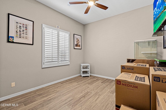 interior space with a ceiling fan, baseboards, and wood finished floors