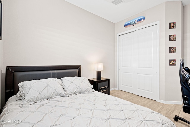 bedroom featuring a closet, wood finished floors, visible vents, and baseboards