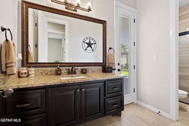 bathroom with wood finished floors, vanity, and baseboards