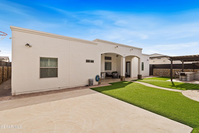 back of property with ceiling fan, fence, stucco siding, a pergola, and a patio area