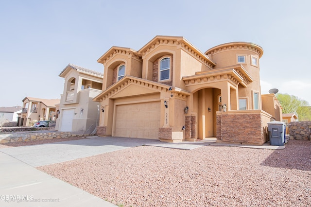 view of front of house featuring a garage, driveway, stone siding, and stucco siding