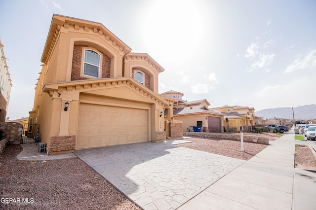 view of front of home with an attached garage, driveway, stone siding, and stucco siding