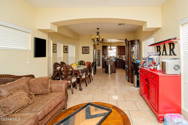 living area with arched walkways, visible vents, a notable chandelier, and light tile patterned floors