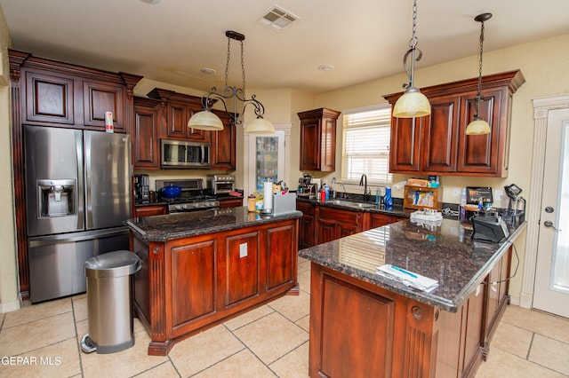 kitchen featuring visible vents, hanging light fixtures, appliances with stainless steel finishes, a sink, and a peninsula