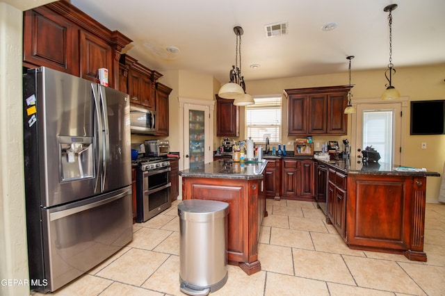 kitchen with a center island, stainless steel appliances, visible vents, dark brown cabinets, and a peninsula