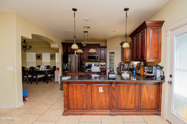 kitchen with light tile patterned floors, a peninsula, visible vents, appliances with stainless steel finishes, and dark stone counters