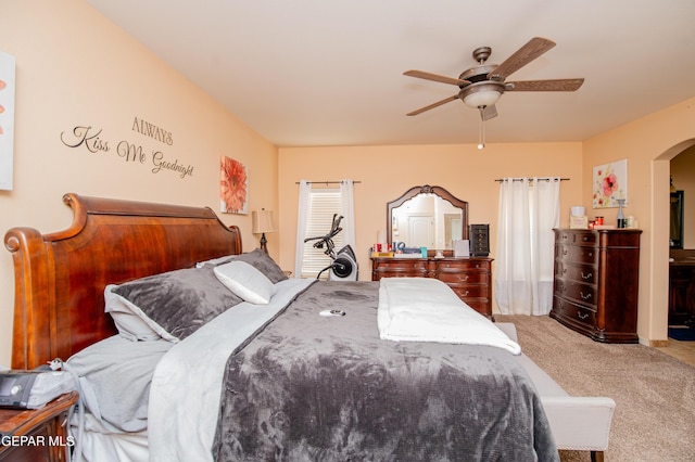 bedroom with a ceiling fan, arched walkways, and light colored carpet