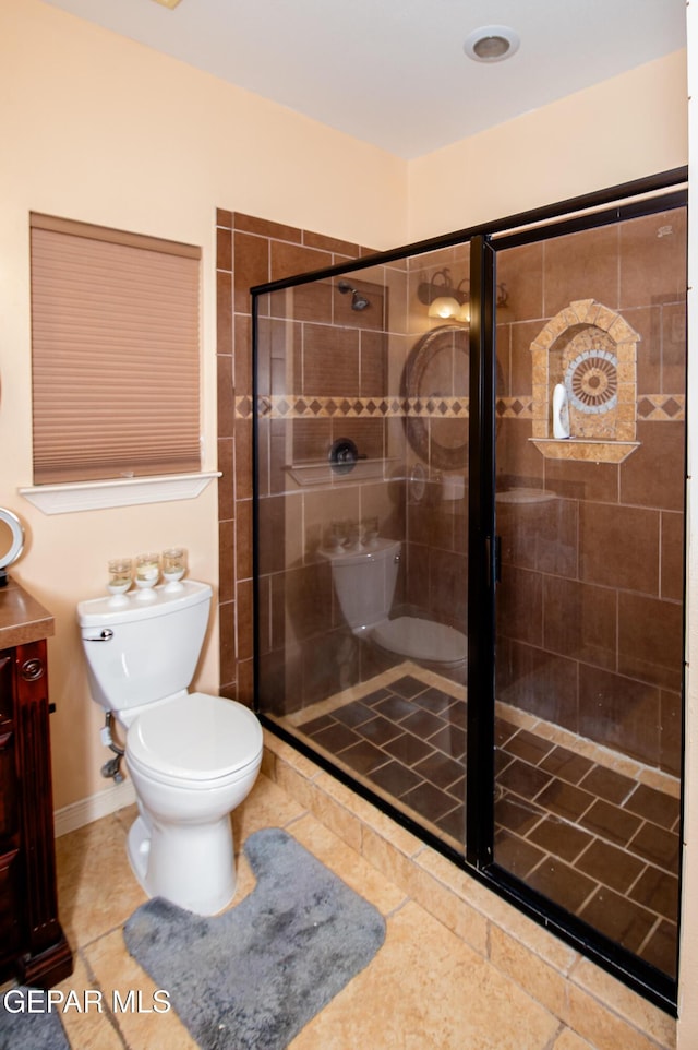 bathroom featuring toilet, a stall shower, tile patterned floors, and vanity