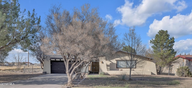 view of front of property with fence, a garage, driveway, and stucco siding