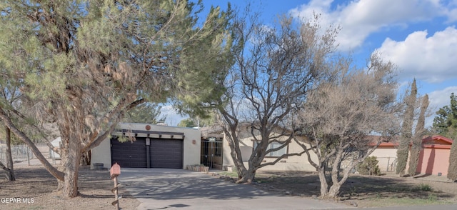 pueblo-style house featuring a garage, driveway, and stucco siding