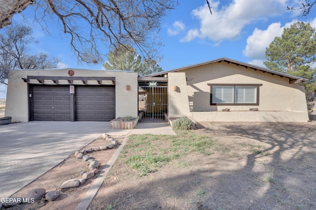 view of front facade featuring an attached garage, a gate, driveway, and stucco siding