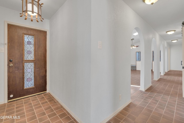 foyer entrance with arched walkways, tile patterned floors, and baseboards