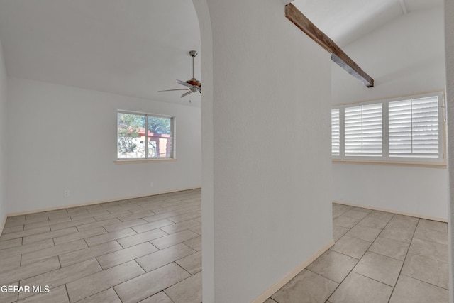 empty room featuring lofted ceiling, arched walkways, and ceiling fan